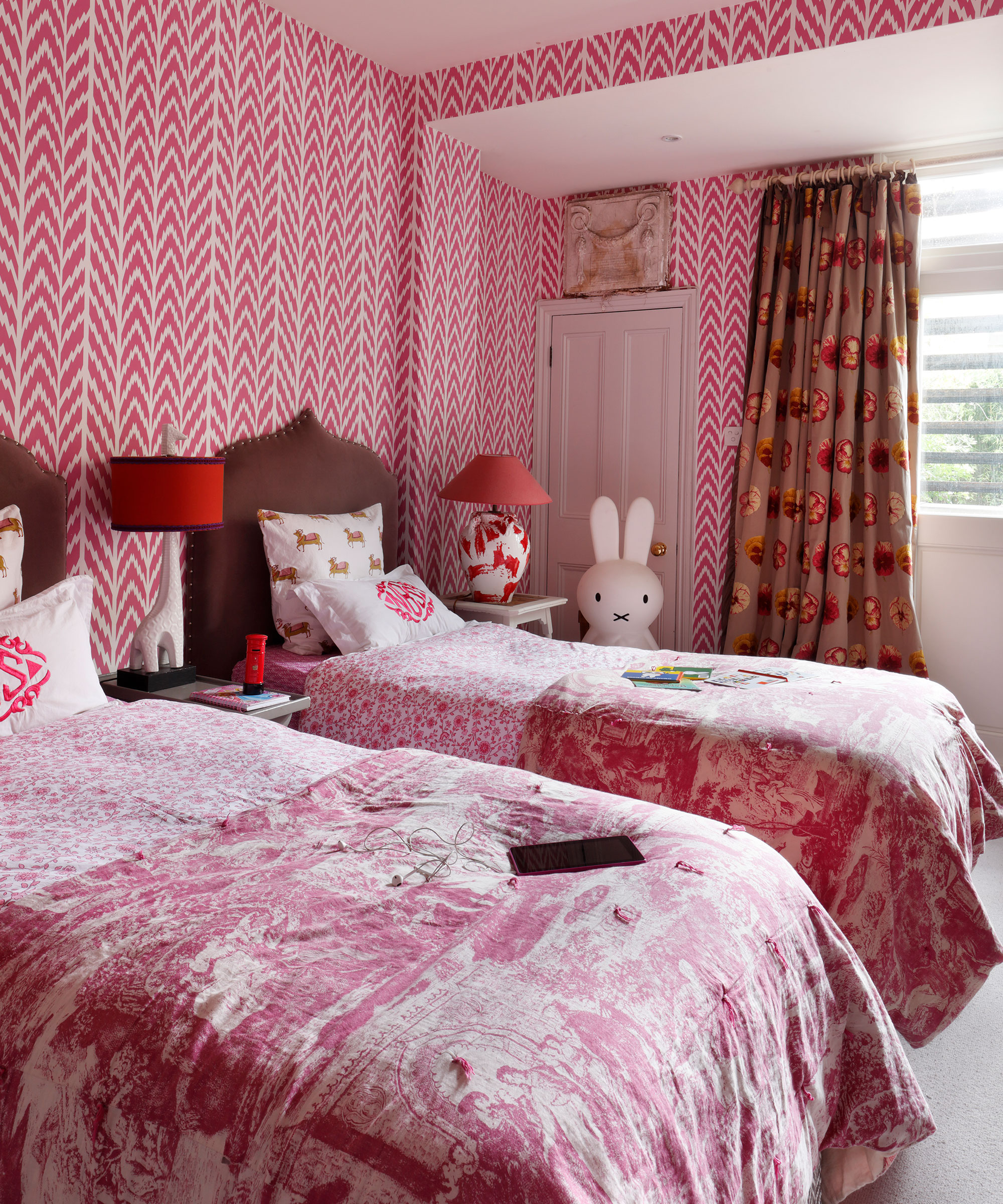 Bright pink kids shared bedroom ideas with patterned wallpaper and twin beds.