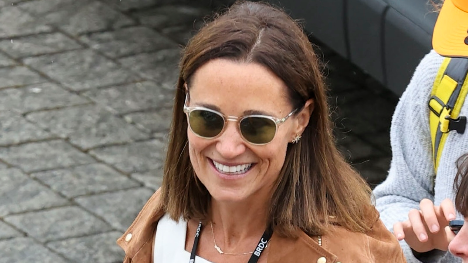 Pippa Middleton wearing a suede jacket and white dress walking outside at British Grand Prix