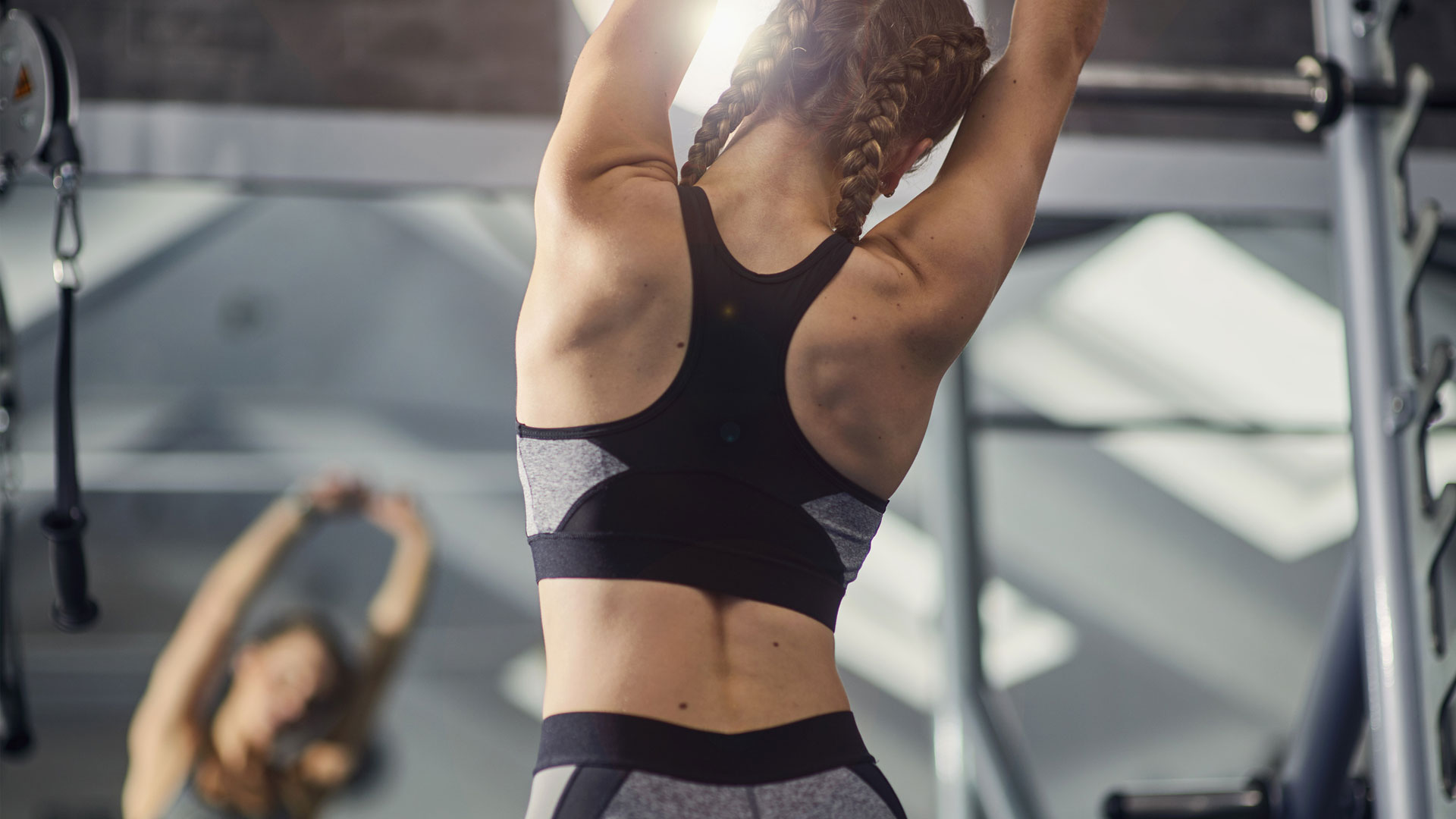 the image shows a woman in the gym stretching