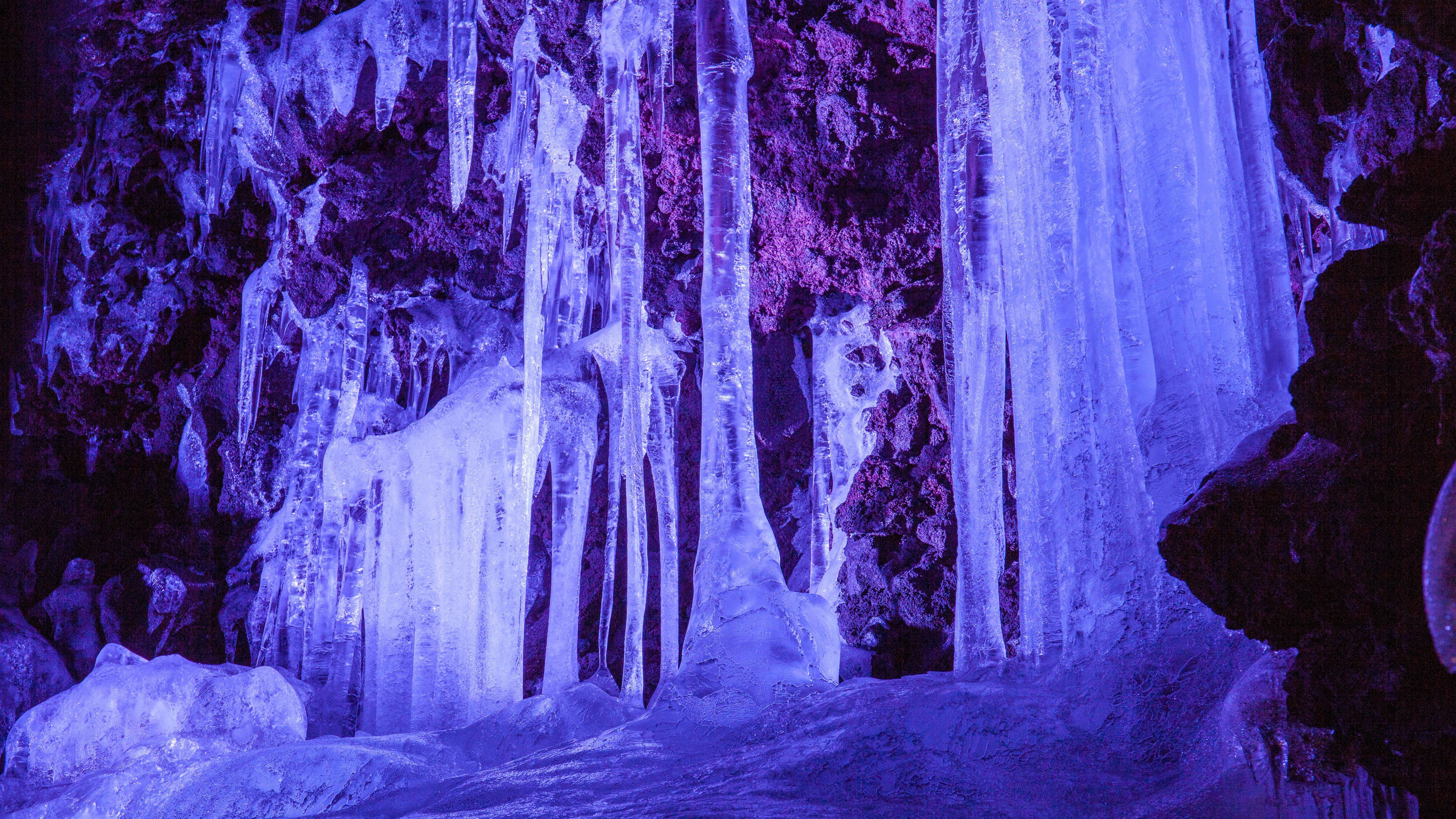 Ice pillars inside the Narusawa Ice Cave. The cave is illuminated with blue light.