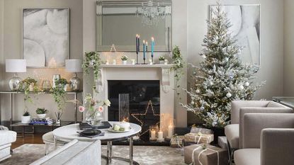 An example of some of the best Christmas decorating ideas—a silver and white living room with Christmas trees, garlands, and candles