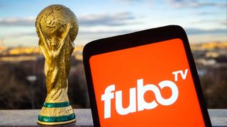 The FuboTV app open on a phone next to the World Cup trophy