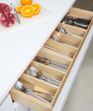 An example of small kitchen storage ideas showing cutlery organizers inside a white kitchen drawer