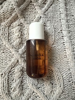 Phlur vanilla skin body mist bottle on a grey weave blanket