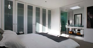 contemporary white bedroom with en suite behind a sleek pocket door design