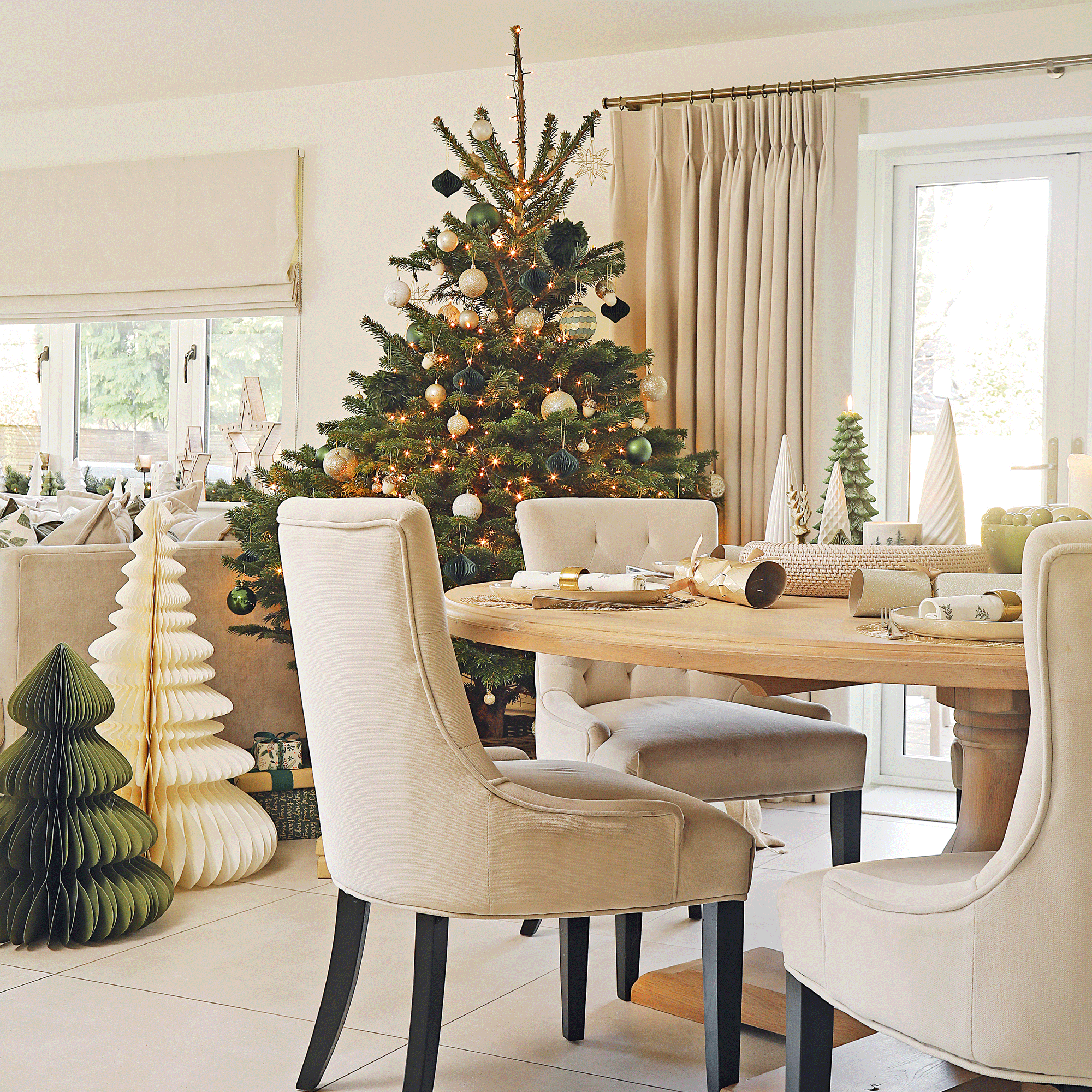 a neutral open plan living dining area with a dining table and Christmas tree, as well as some large paper trees