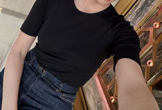 Woman wearing a black T-shirt and dark-wash jeans.