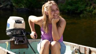 Maisy Stella as Elliott in My Old Ass driving a boat and smiling with her right hand on her chin.