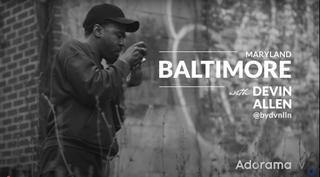 Monochrome screenshot of Devin Allen from Adorama's Picture America video series standing next to graffiti-covered wall