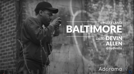 Monochrome screenshot of Devin Allen from Adorama's Picture America video series standing next to graffiti-covered wall 
