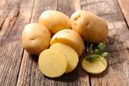 Whole And Sliced Potatoes On A Wooden Surface