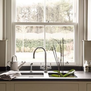 Double kitchen sink with silver taps in front of a large window