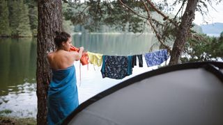A woman hangs her clothes up to dry at camp