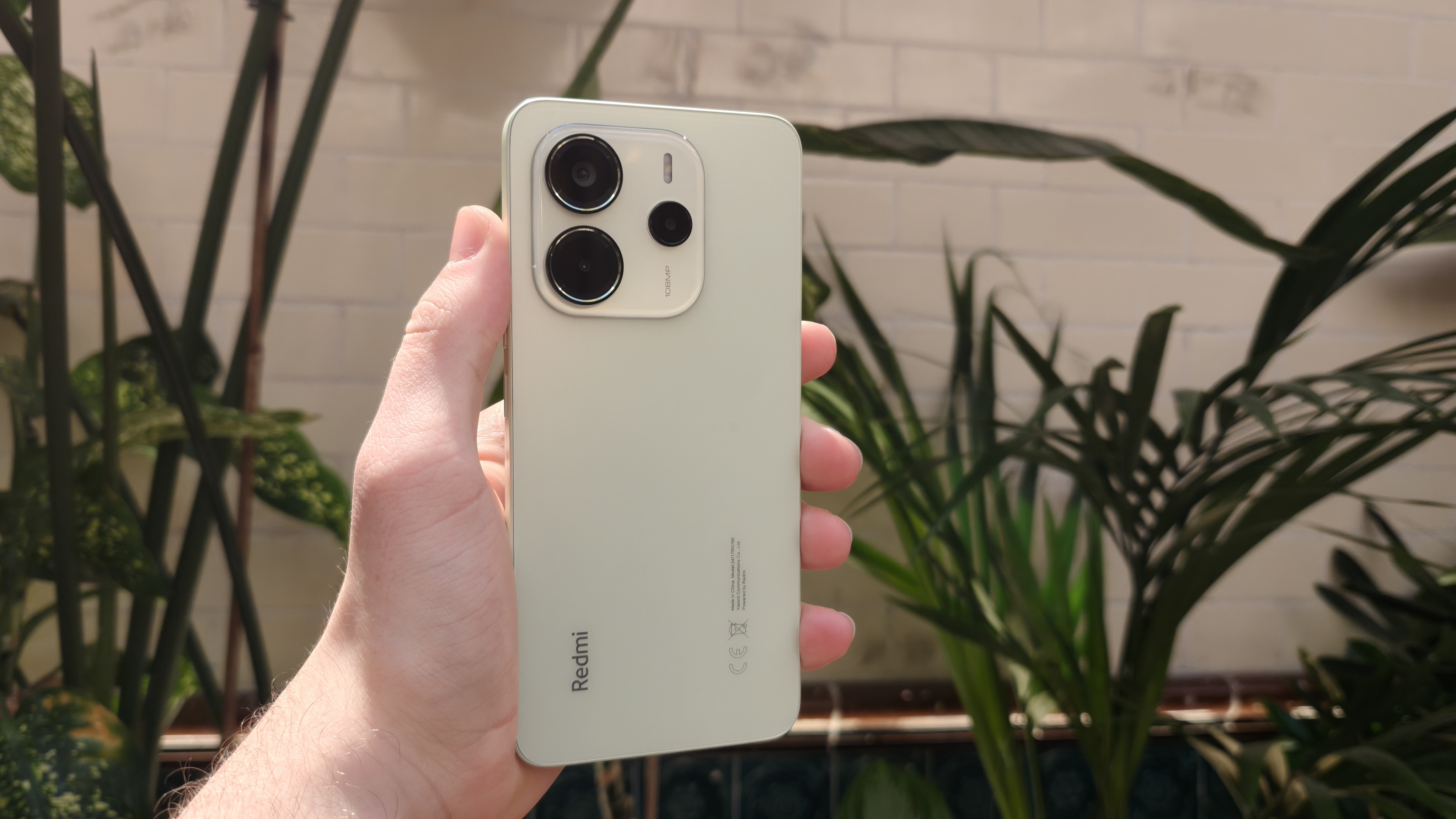 The Redmi Note 14 against a houseplant