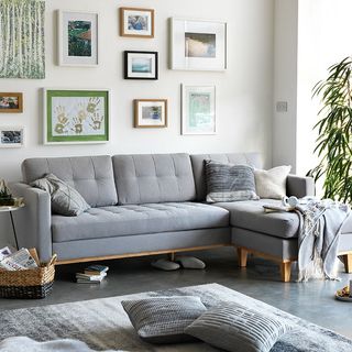 living area with photo frame on white wall and grey sofa set and floor mat with cushion