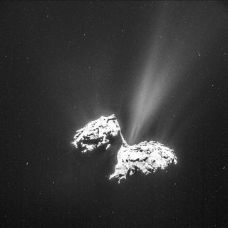 Comet hangs in starry space with bright jets of gas flying out