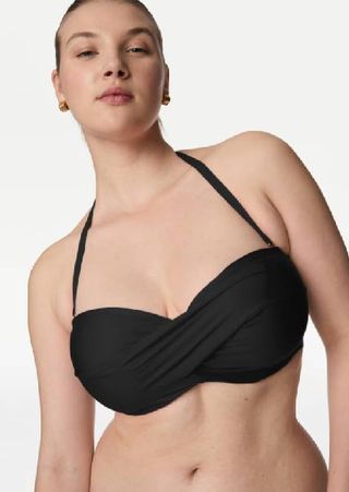 A close up of a model wearing a black twist bikini top from M&S.