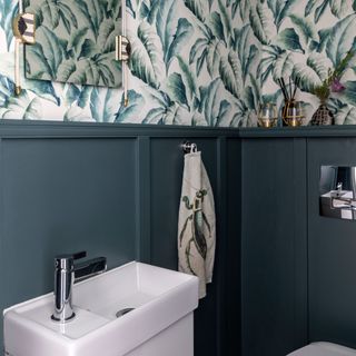 Cloakroom with navy wall panelling and tropical wallpaper