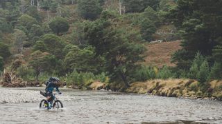 Mountain biker riding over river Feshie