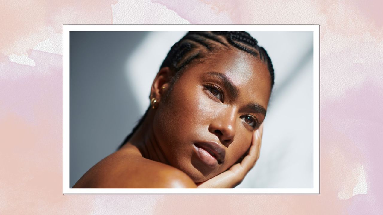 a pink watercolour backdrop containing an image of a woman with glowing smooth skin, who is resting her face in her hands