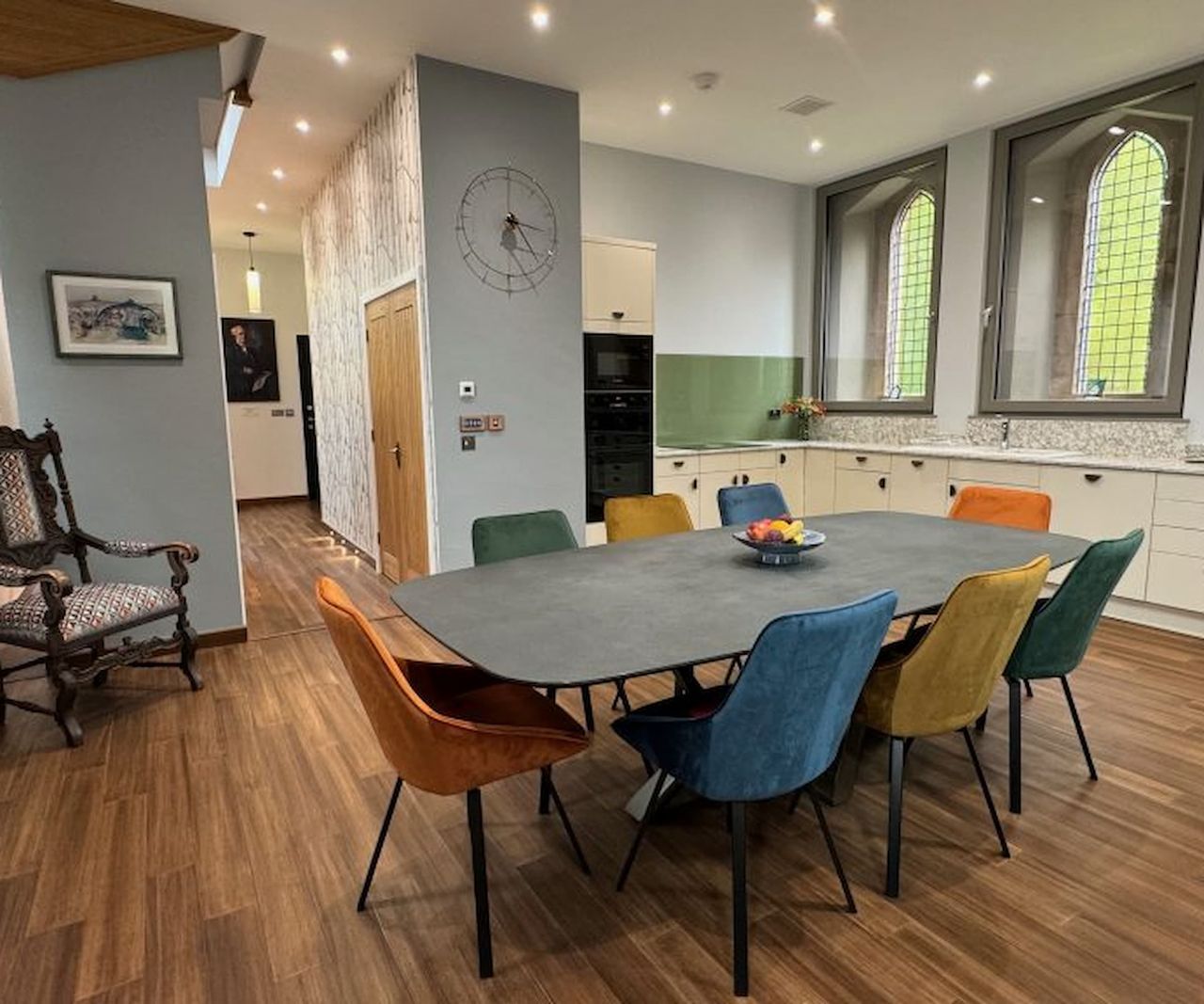 An open plan kitchen with wooden floors and a kitchen table in the middle