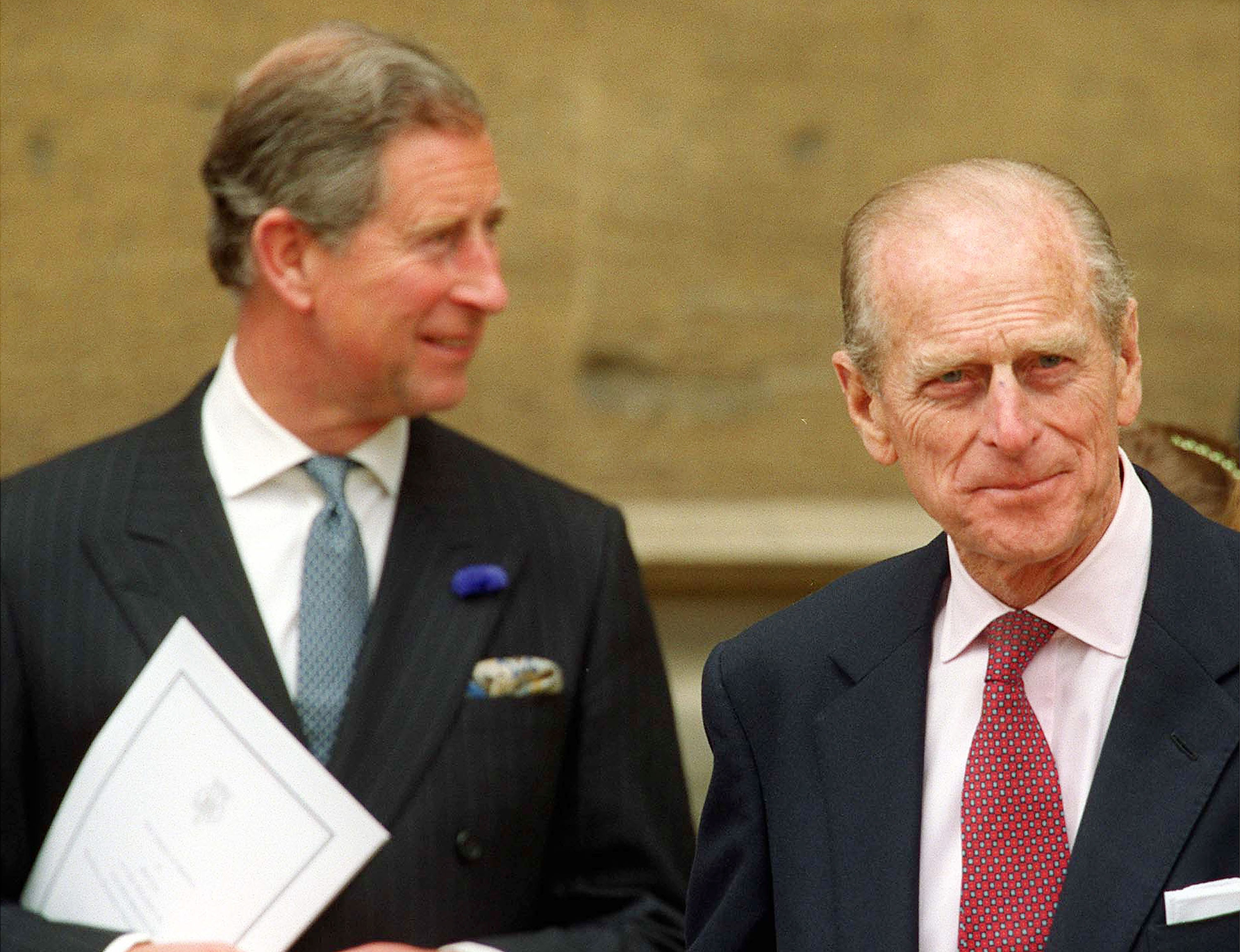 Prince Charles and Prince Charles smiling and wearing suits standing next to each other