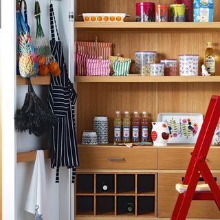 Open kitchen larder unit with wooden interior showing shelving and drawers