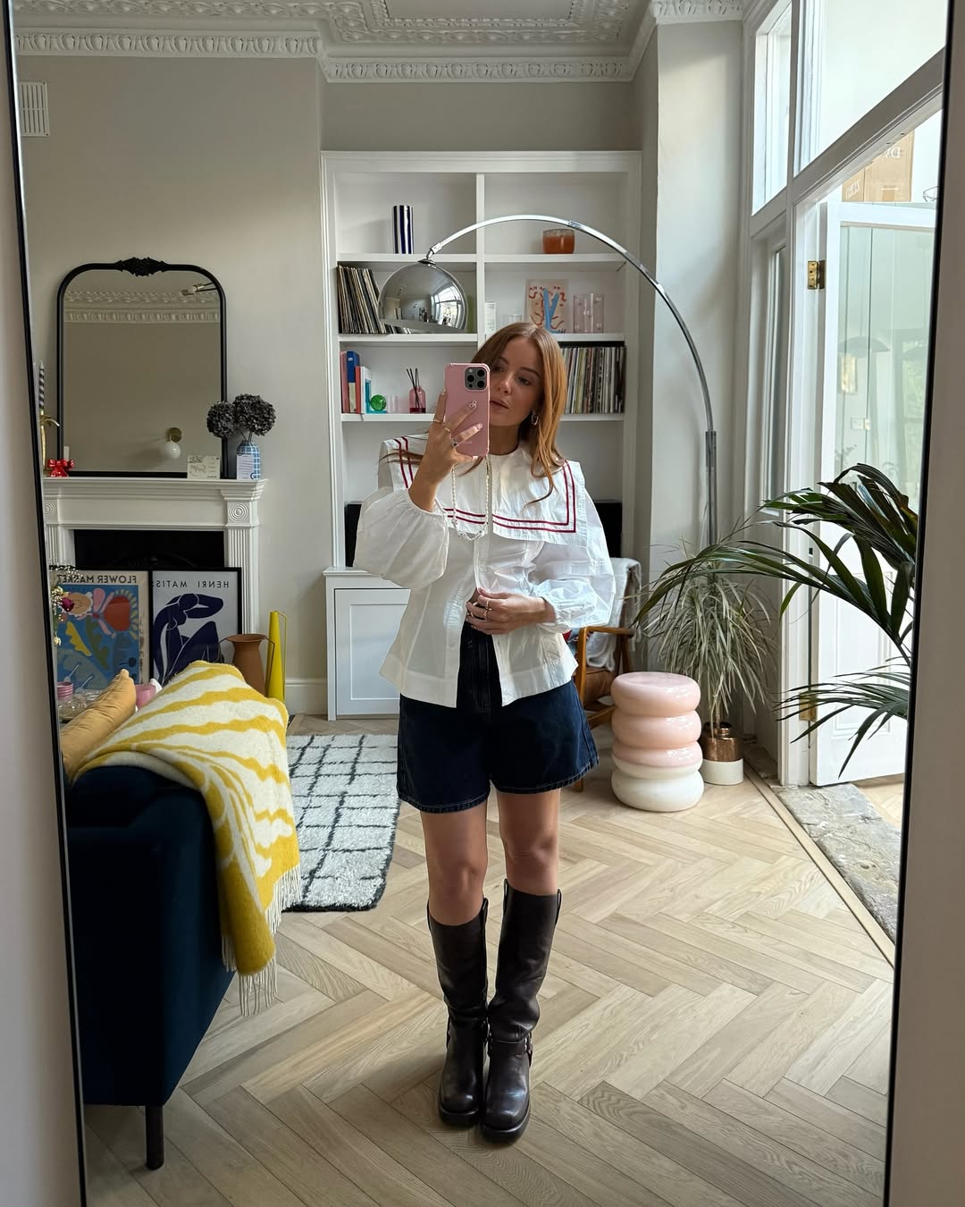 Influencer Rebecca Ferraz Wyatt in biker boots blue denim jorts, a white cotton poplin top with red trim.