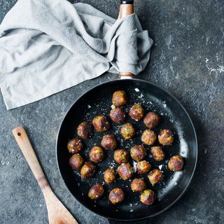 meat balls in iron pan with wooden handle and cleaning cloth