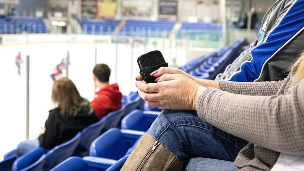 Person holding a Zippo hand warmer in the crowd at an ice hockey game