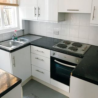 A small kitchen with white gloss cabinetry, 4-hob cook surface, stainless steel kitchen sink, and bottle of Fairy washing-up liquid