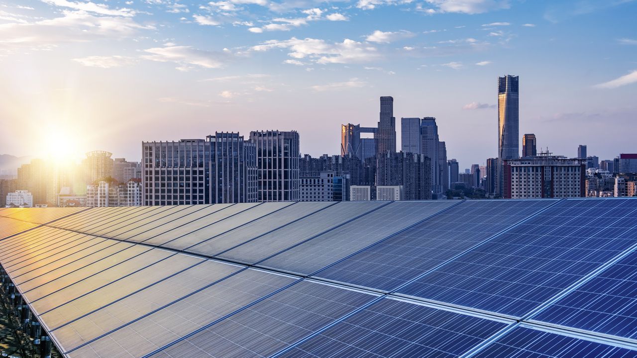 Solar panels with a city skyline in the background.