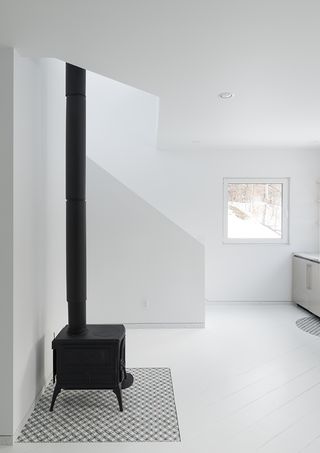 black stove within minimalist white interior in Vermont cabin