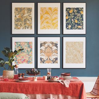 table with red tablecloth and posters in frames on gallery wall