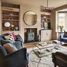 A soft peach colour-painted living room with a blue velvet sofa, a globe table lamp and wall lights in an alcove and a sculptural ceiling light