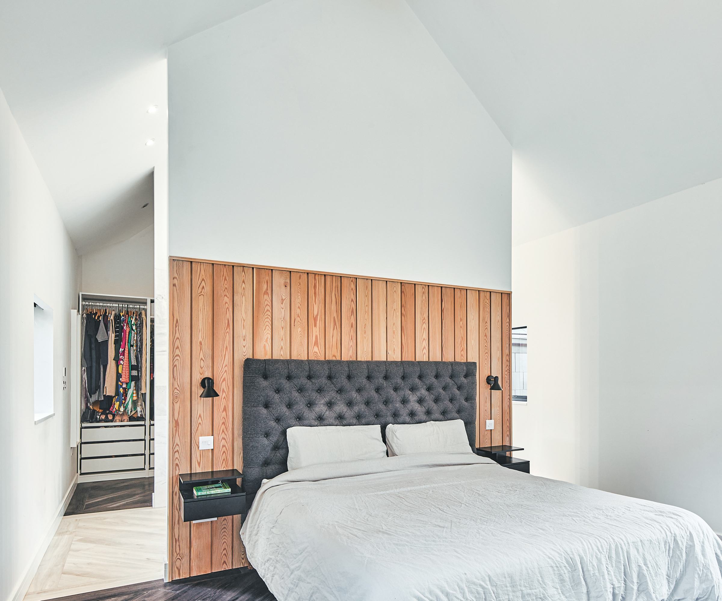 dividing wall in bedroom panelled with wood on lower half and behind visible dressing area