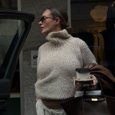 Woman wears funnel neck jumper and tailored trousers