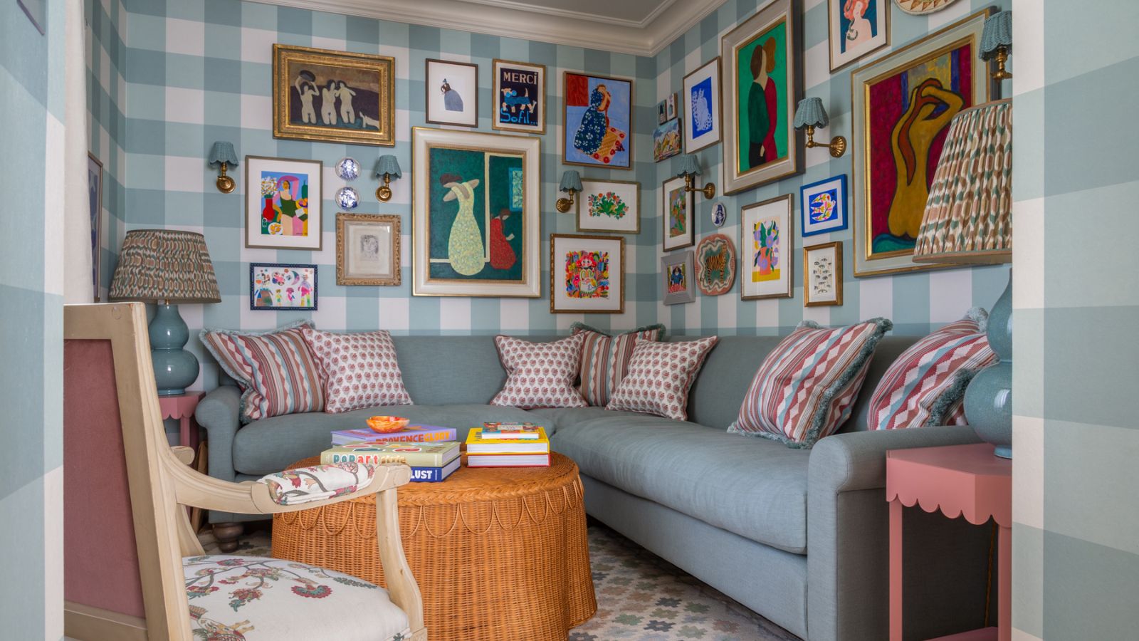 preppy snug room with blue and white gingham wallpaper, a gallery wall, light blue corner sofa with a rattan scalloped coffee table