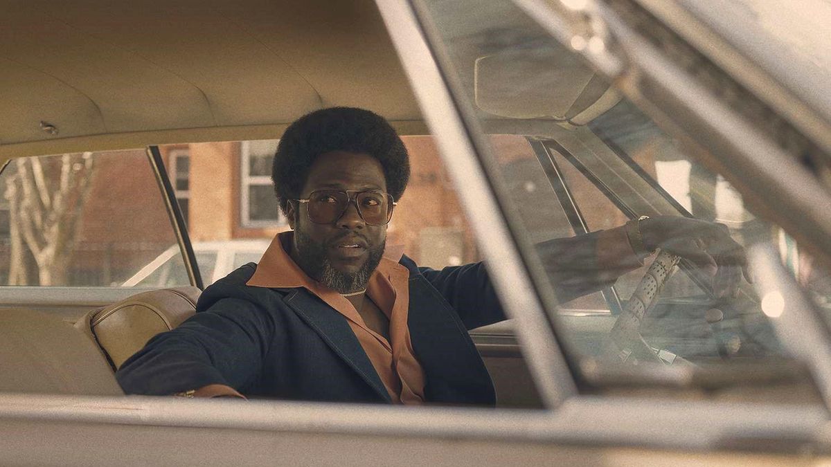 Kevin Hart in a car in a 1970s suit as Chicken Man in Fight Night: The Million Dollar Heist.