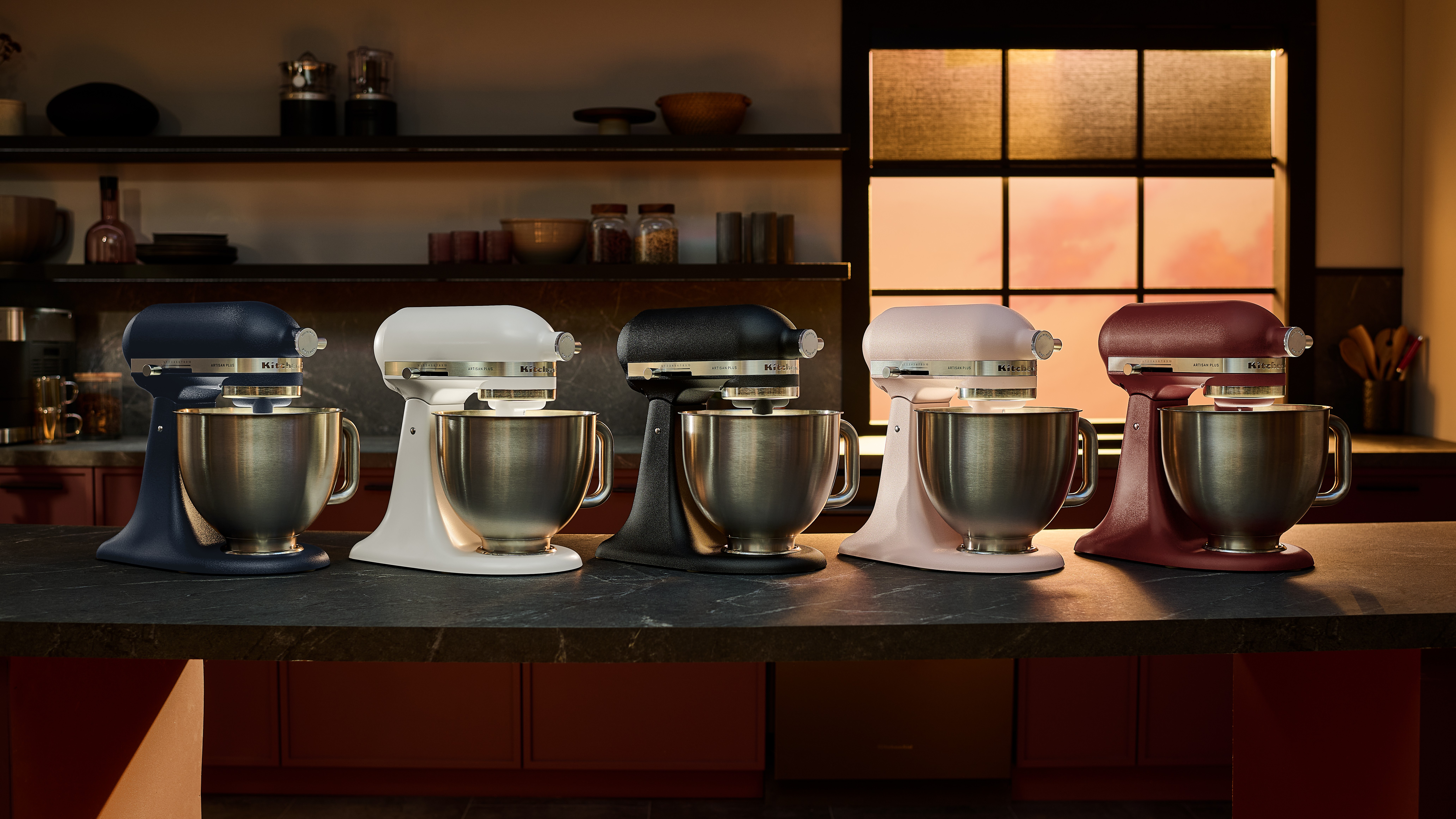 Five KitchenAid Artisan Plus stand mixers in different colors on kitchen counter