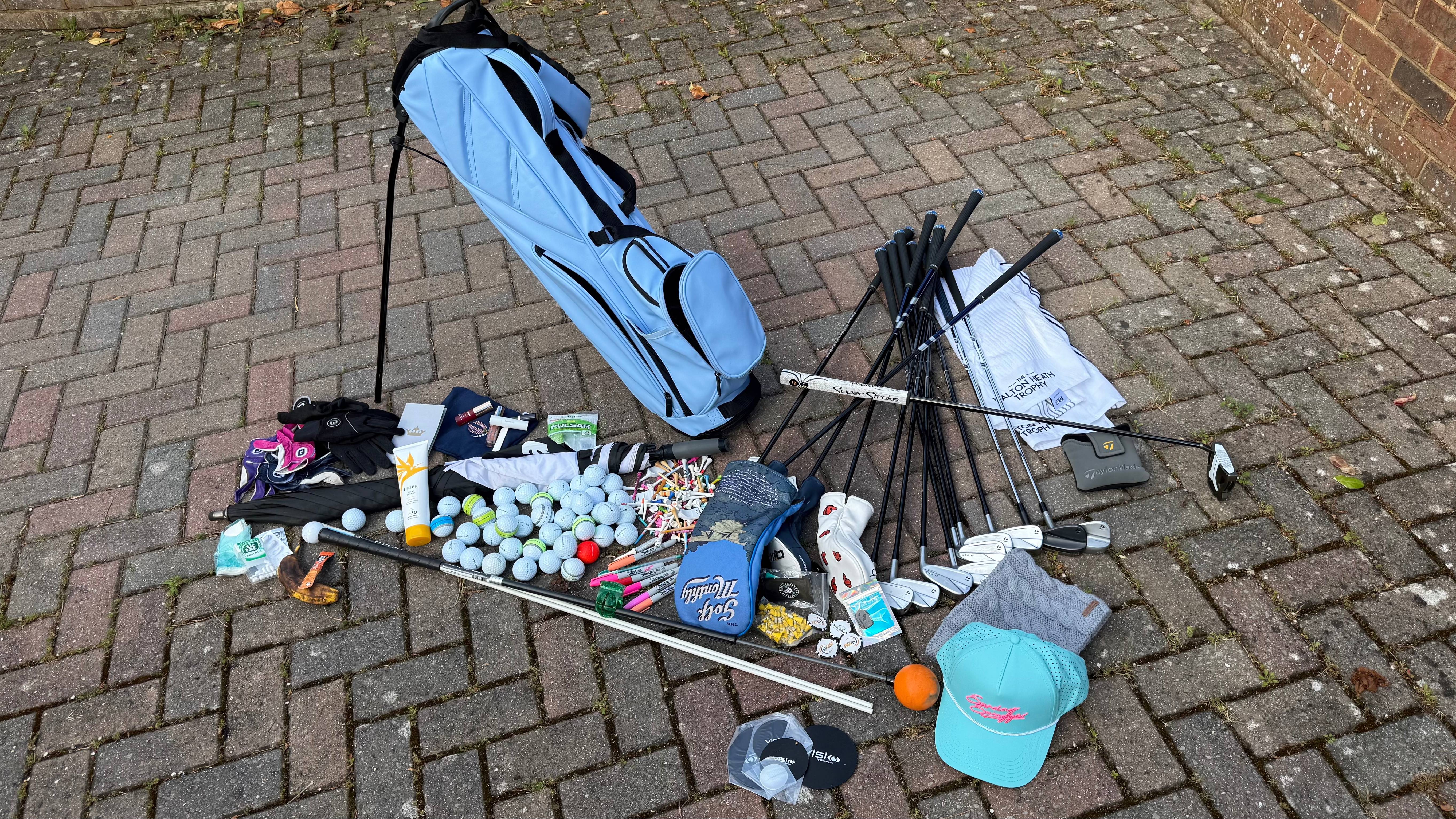 A golf bag with all its contents on the ground for a clear out