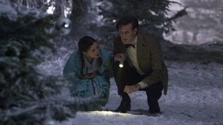 The Doctor squats with a woman in a snowy area in The Doctor, The Widow and the Wardrobe