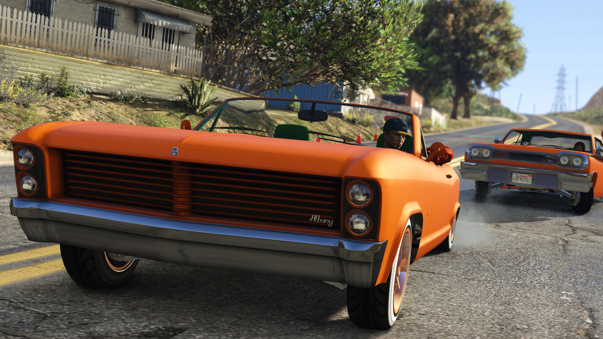 Two bright orange cars driving in single-file on a sunny day in GTA Online