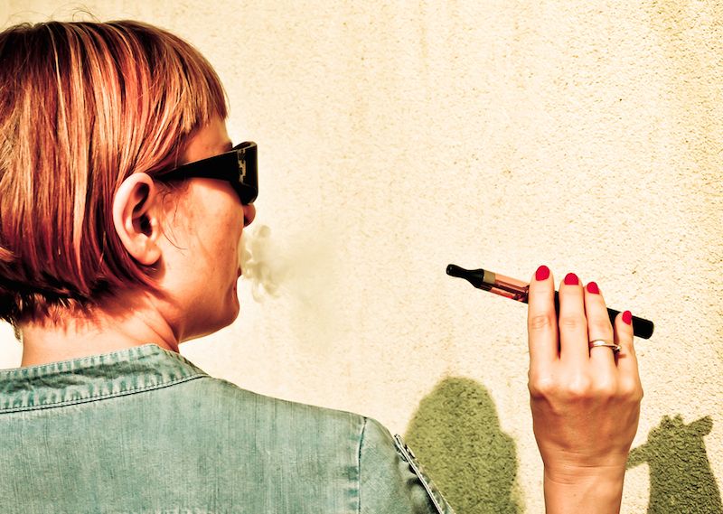 A woman smokes an electronic cigarette.