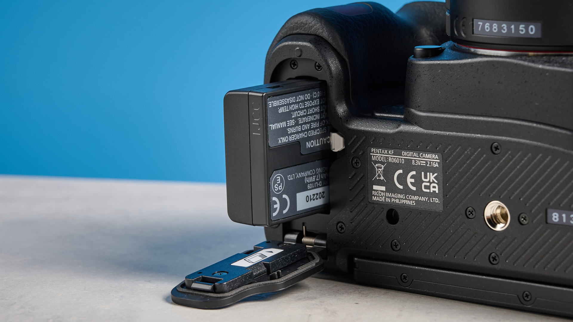 Pentax KF DSLR camera photographed on a blue background