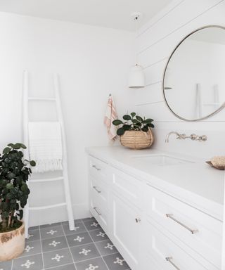 White half bath with round mirror and house plant