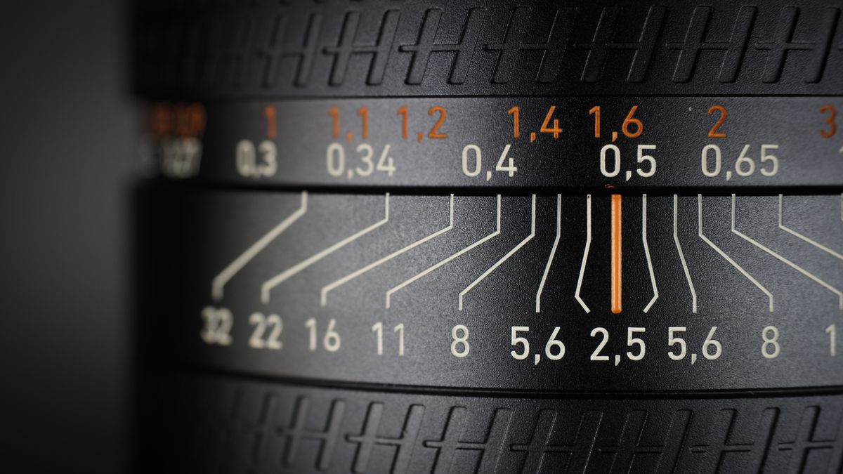 Hasselblad XCD 25V lens, on a wooden table, shot with dramatic light against a dark background