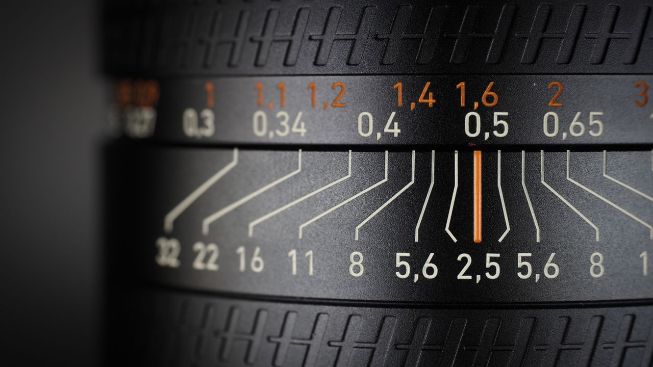 Hasselblad XCD 25V lens, on a wooden table, shot with dramatic light against a dark background