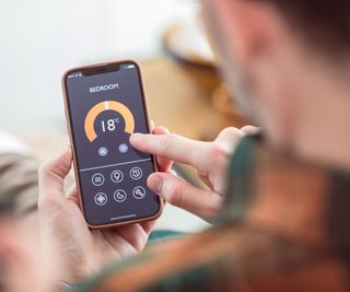 man using phone to control bedroom temperature via an app