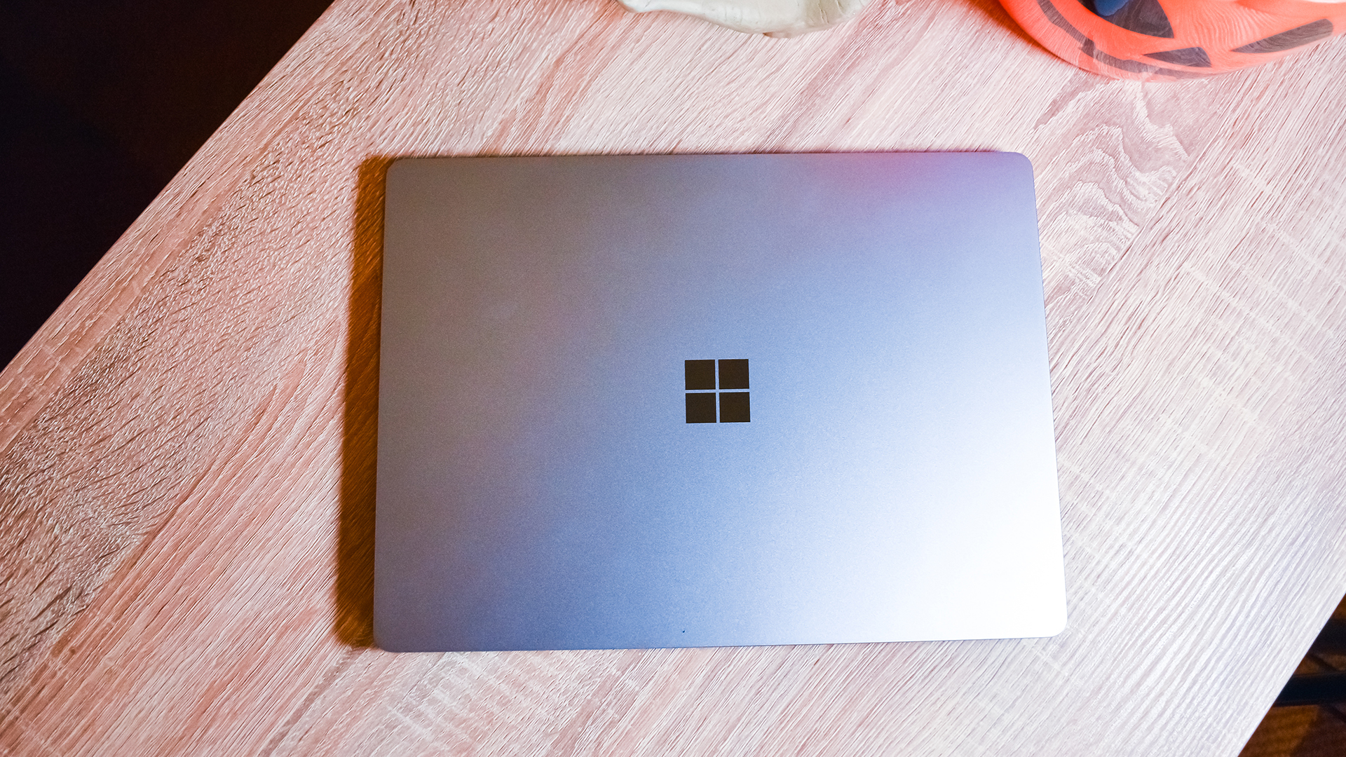 Surface Laptop Go yang tertutup diletakkan di atas meja kayu